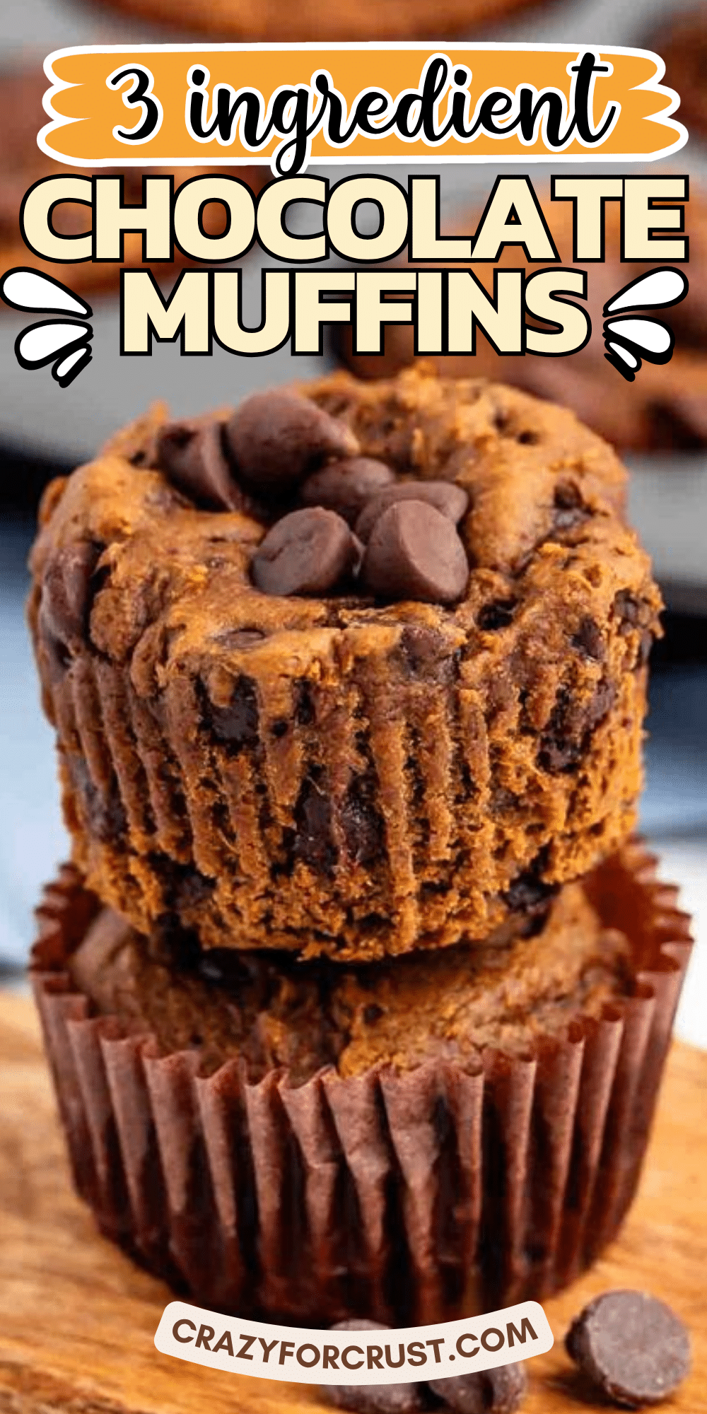 Two chocolate chip muffins stacked on a wooden board, with extra chocolate chips on top. Text on the image reads 3 ingredient chocolate muffins.