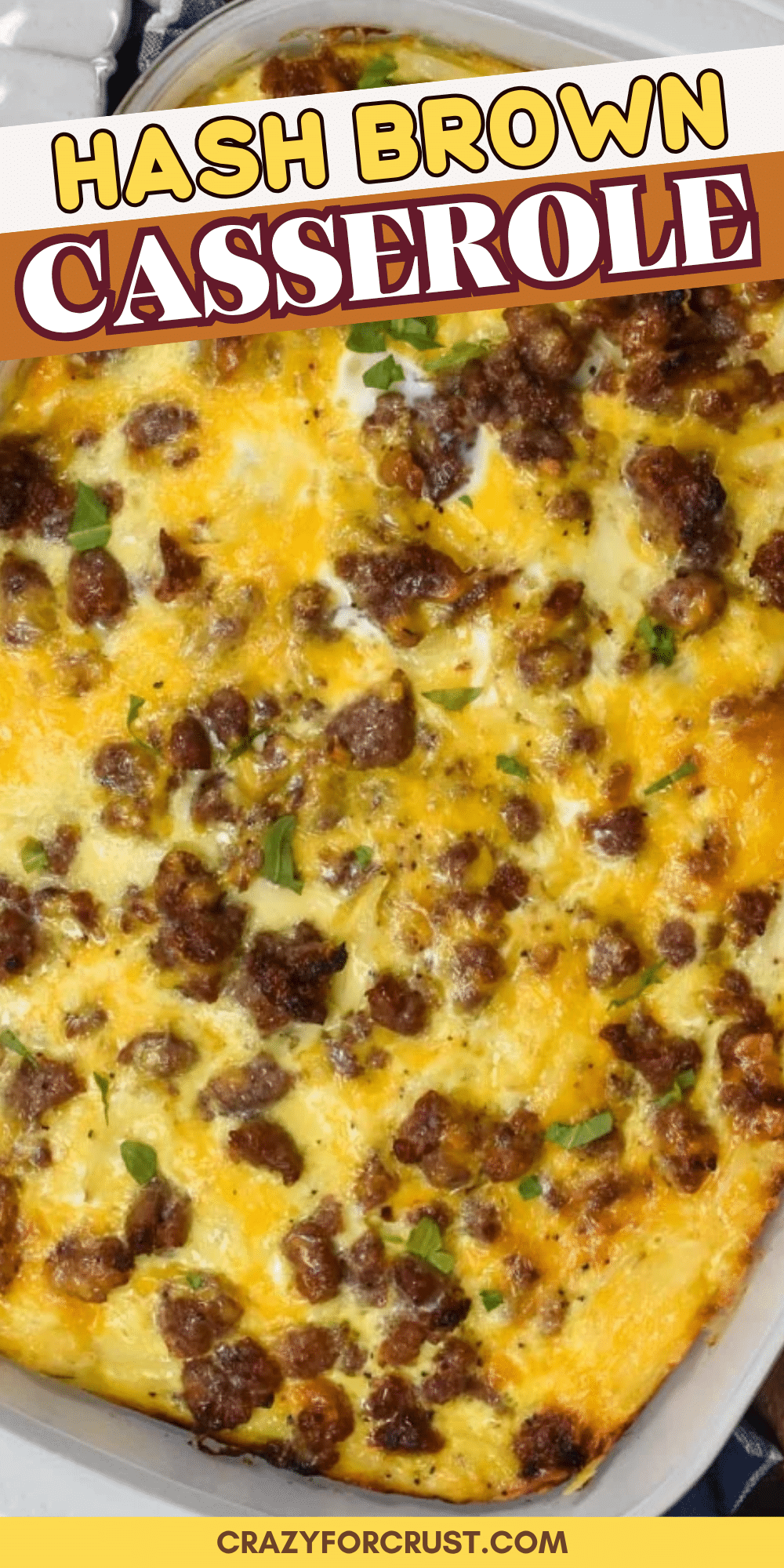 A baked hash brown casserole topped with browned sausage and melted cheese, garnished with herbs, in a rectangular dish. Text overlay reads “Hash Brown Casserole.”.