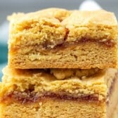 Two golden brown bars stacked, each with a layer of red jam filling in the center and a crumbly, textured top and bottom crust.