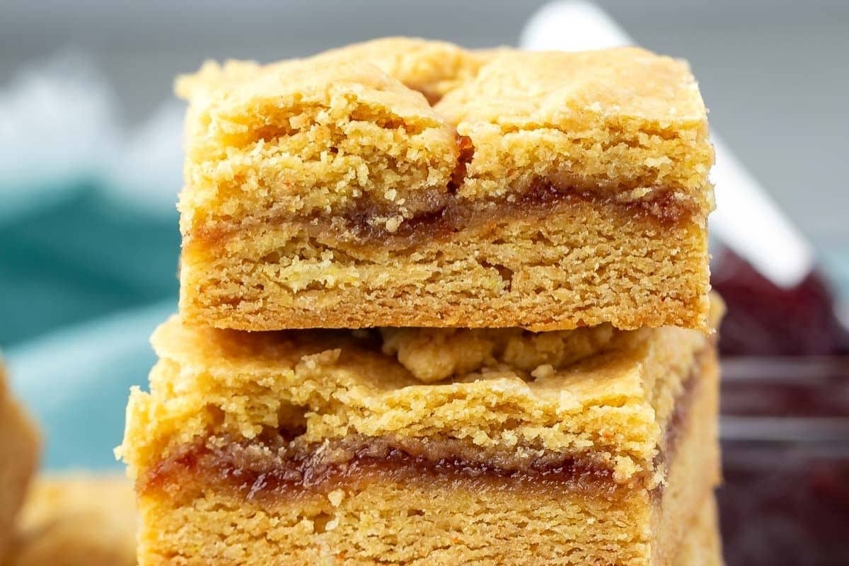 Two golden brown bars stacked, each with a layer of red jam filling in the center and a crumbly, textured top and bottom crust.