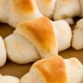 Golden brown, homemade crescent rolls arranged in a circle on a baking sheet, showing their fluffy, soft texture and slightly crisp tops.