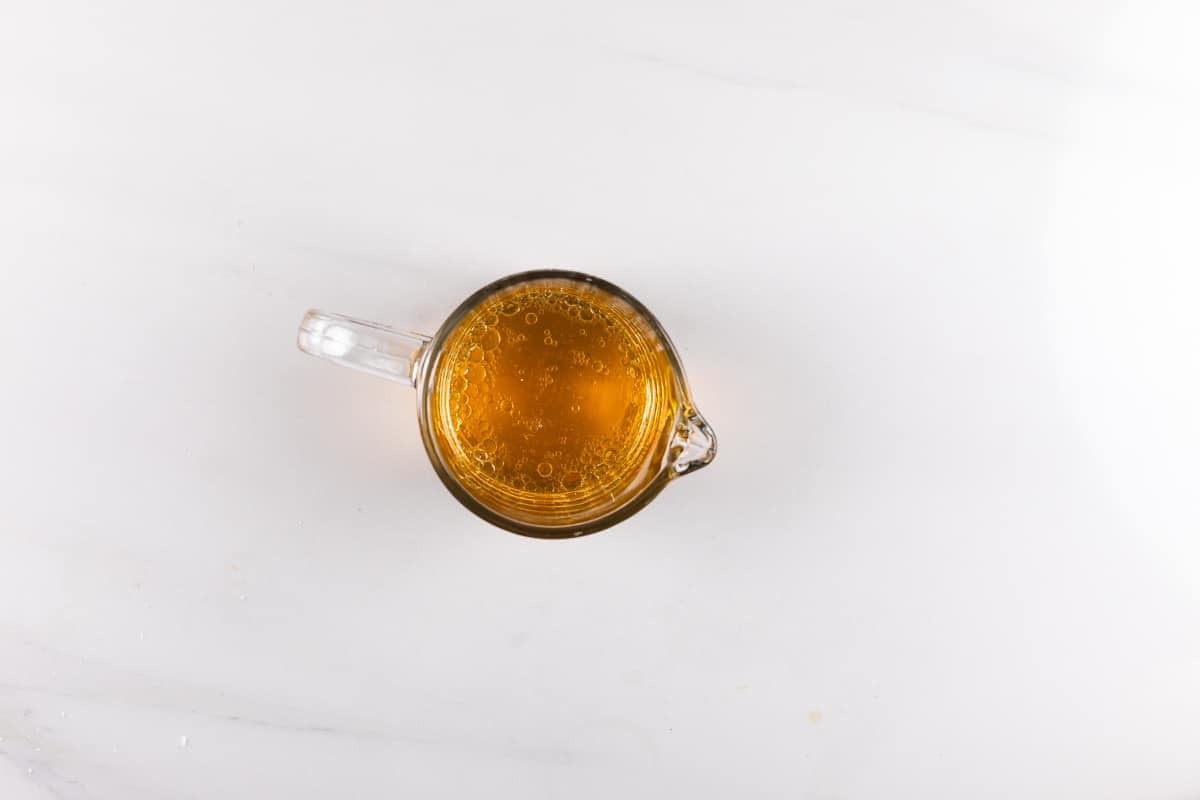 A glass mug filled with amber-colored liquid, viewed from above, placed on a white marble surface.