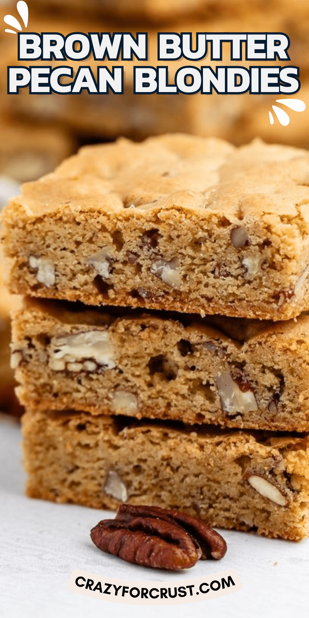 A stack of three thick, golden-brown blondies studded with chopped pecans, with a single whole pecan sitting in the foreground. Text at the top reads BROWN BUTTER PECAN BLONDIES, and the bottom text reads CRAZYFORCRUST.COM..