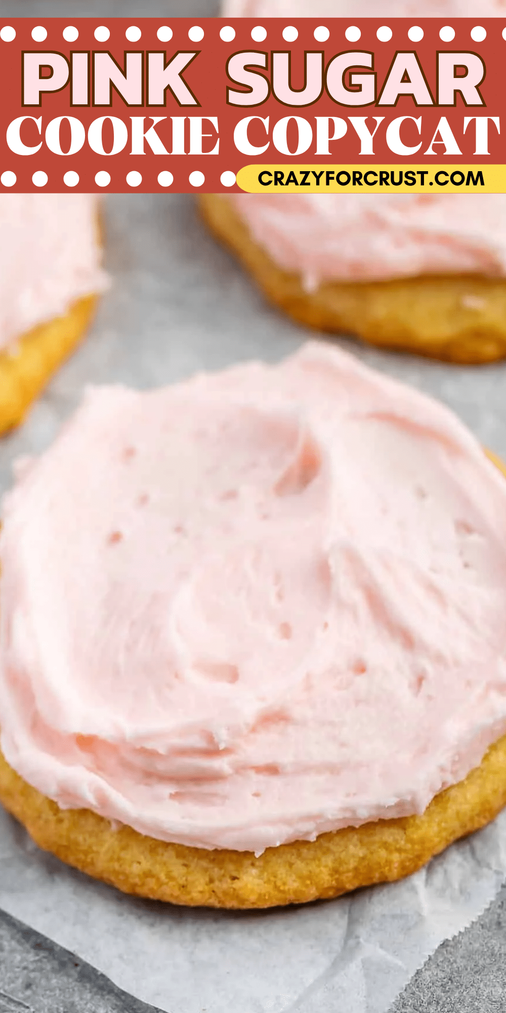 Close-up of a sugar cookie topped with pink frosting on parchment paper. Text at the top reads, Pink Sugar Cookie Copycat and crazyforcrust.com..