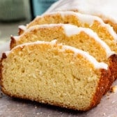 A sliced loaf of golden pound cake topped with white glaze.