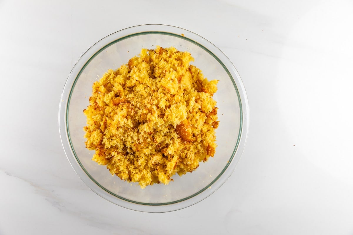 Crumbled yellow cornbread in a clear glass bowl.