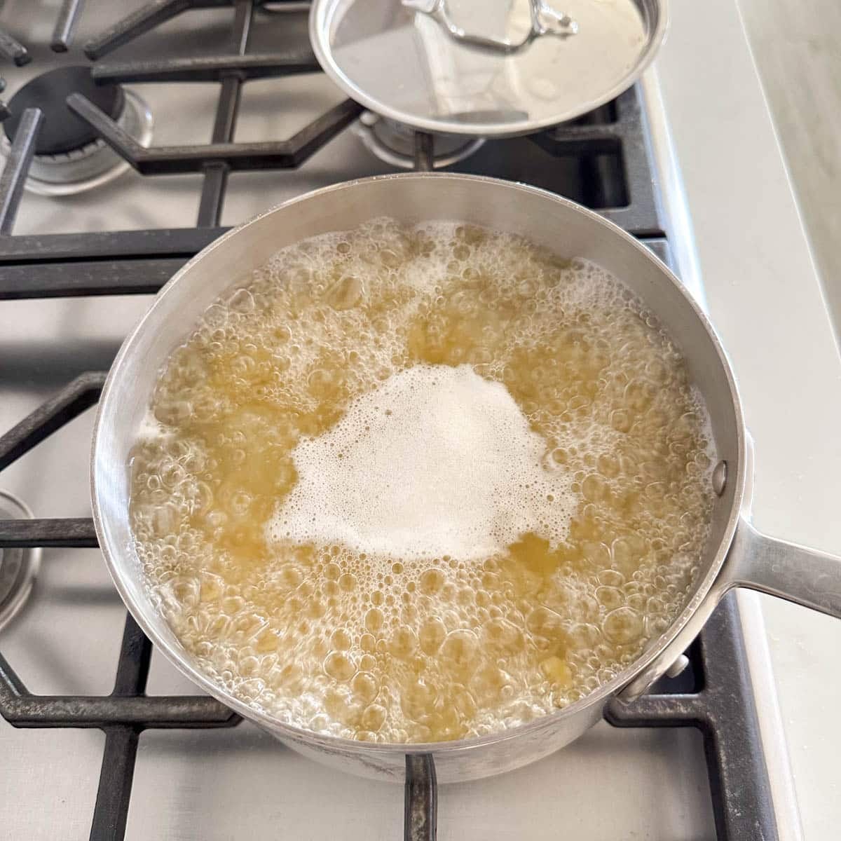 A metal pot of boiling pasta on a gas stove.