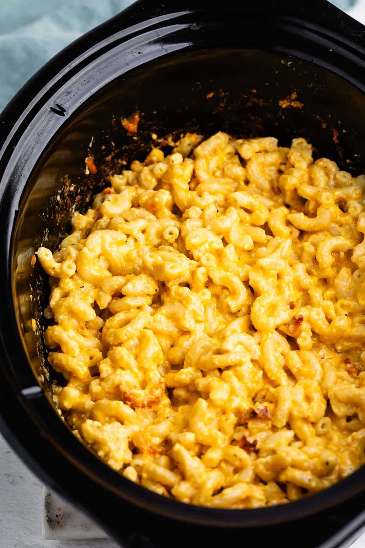 Macaroni and cheese in a black slow cooker.