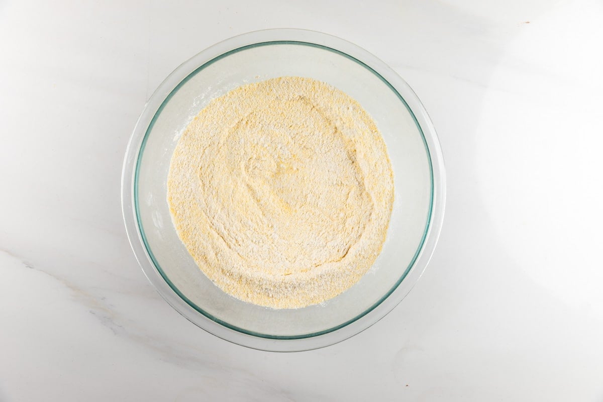 A glass bowl filled with yellow cornmeal or flour.
