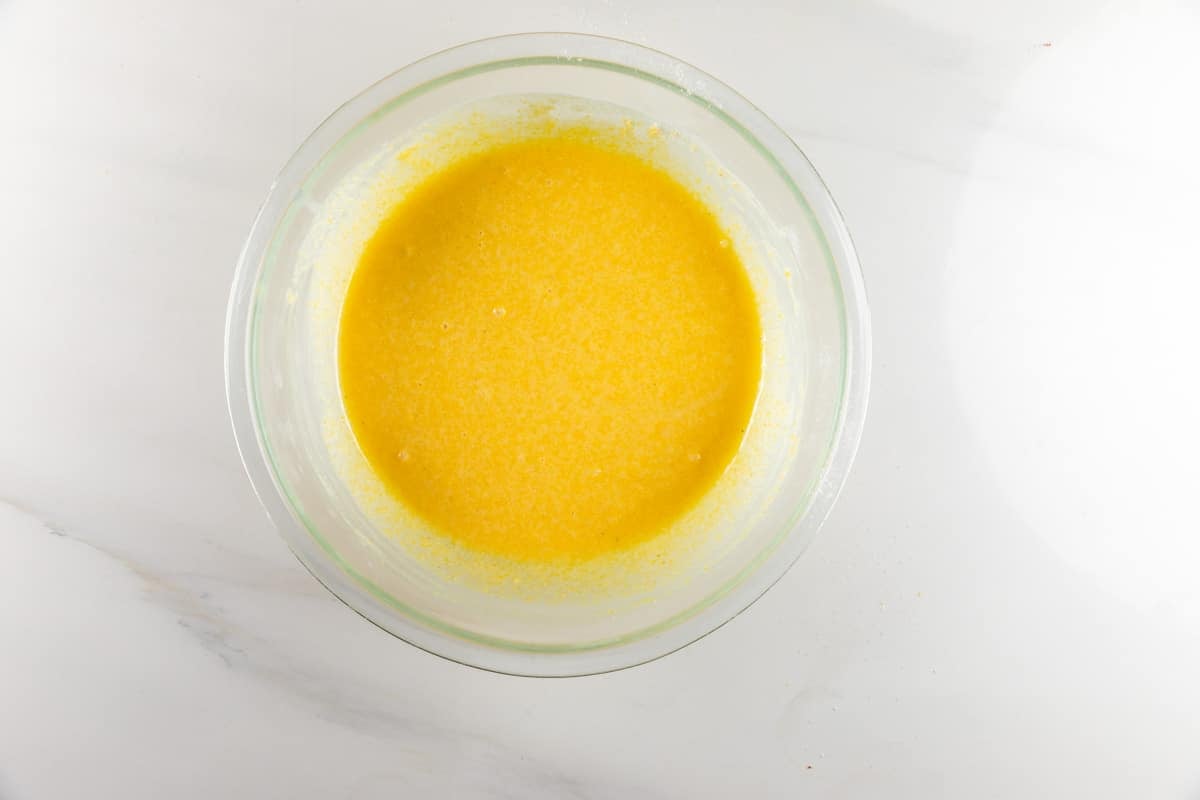 Yellow cake batter in a clear glass mixing bowl.