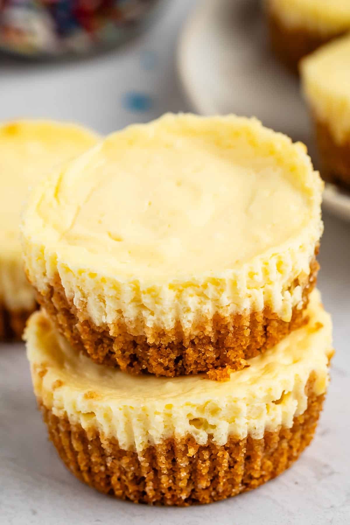 Two mini cheesecakes stacked on a light surface.