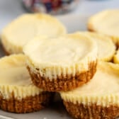 A pile of mini cheesecakes with golden-brown crusts on a plate.