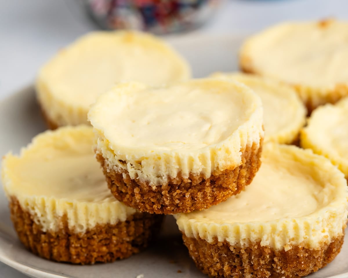 A pile of mini cheesecakes with golden-brown crusts on a plate.