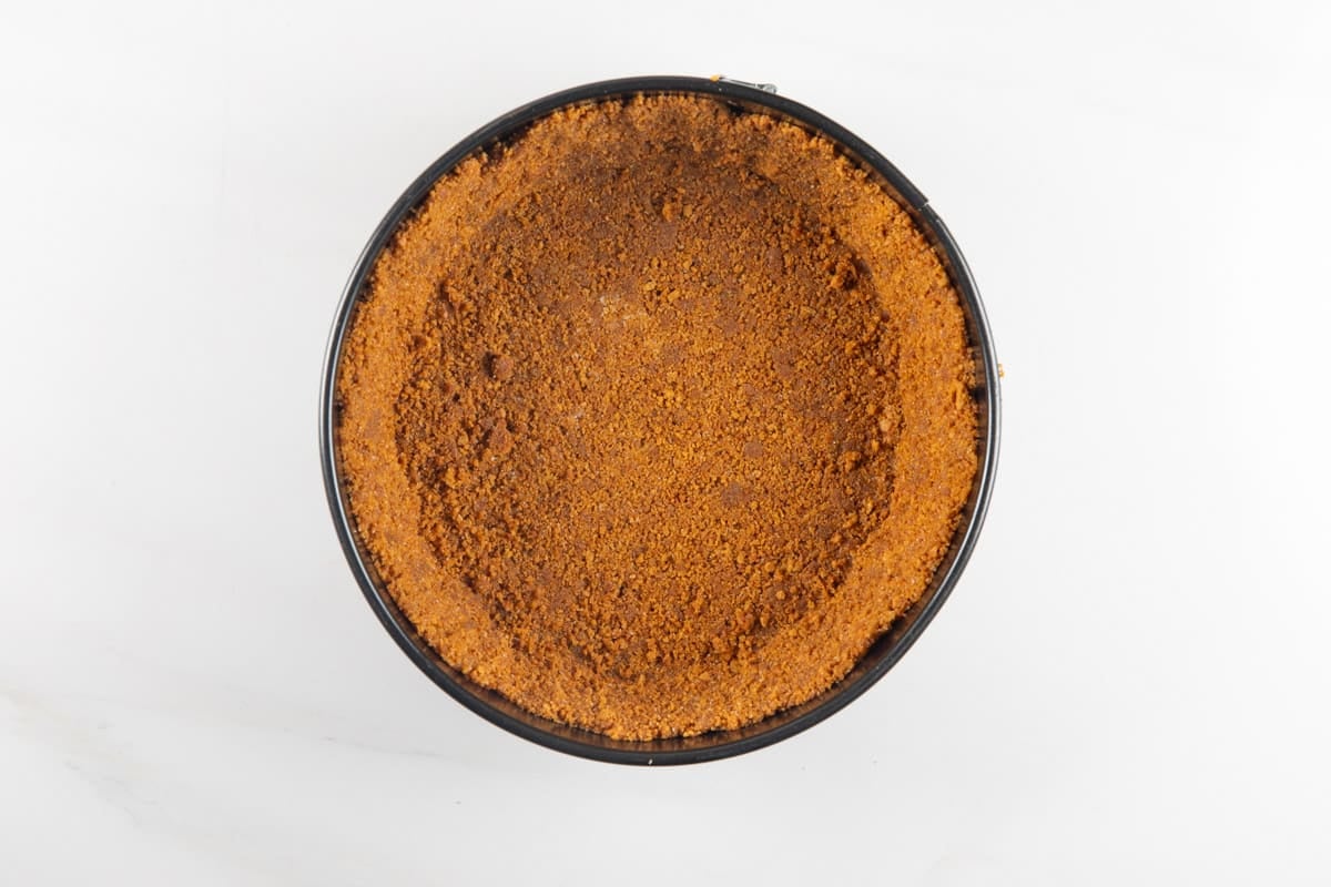 A pressed cookie crumb crust inside a round springform pan.