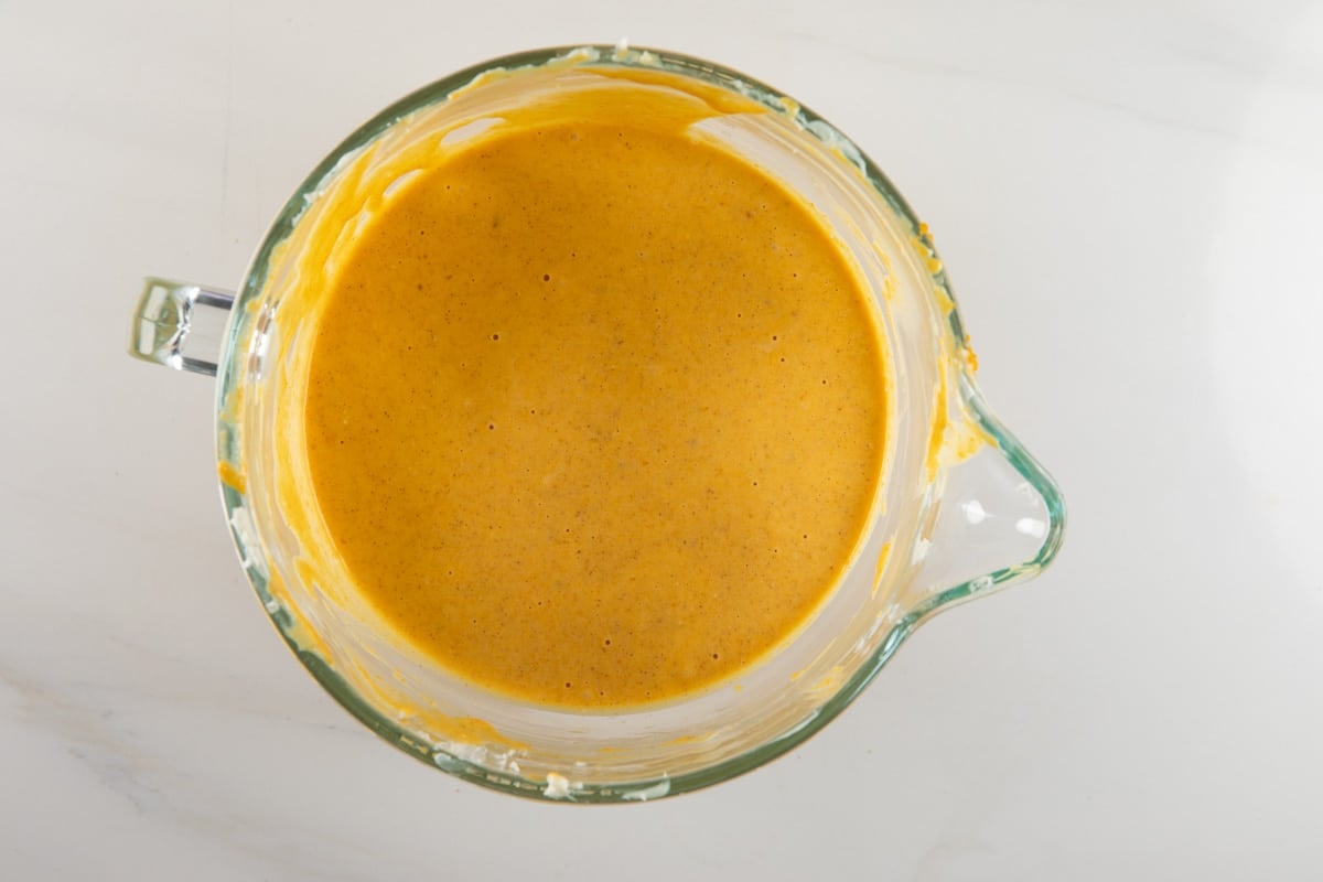 Smooth orange batter in a glass measuring cup viewed from above.